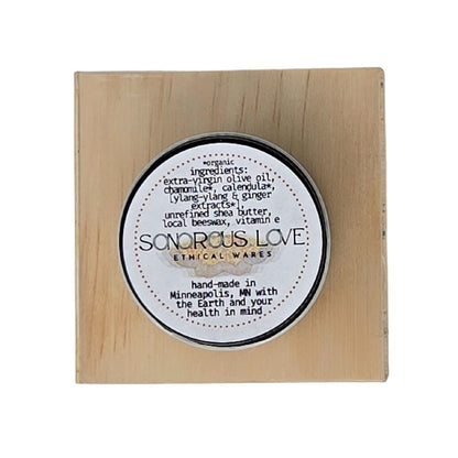 Hand-made herbal medicinal balm top view of label ingredients of ginger and ylang-ylang essential oils in a glass amber jar. 