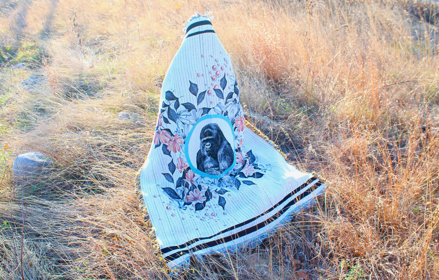 Sonorous Love, Majesty, inspired by the beauty of the endangered Mountain Gorilla, gentle giants of central Africa. Natural, stripe and floral portrait with sherbet orange pearls; eco-friendly woven throw blanket