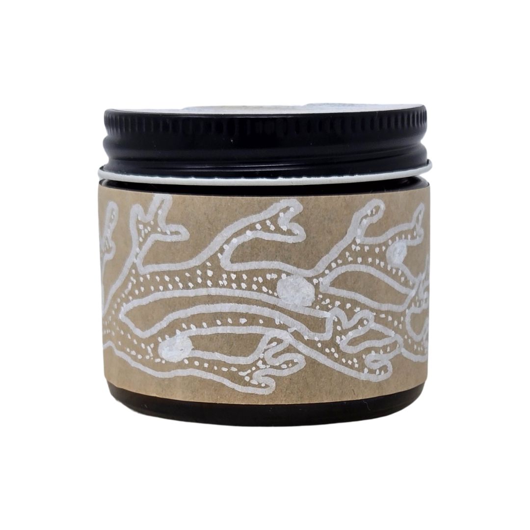 Amber jar with decorative, hand-drawn label and black lid on a white background. 2 oz